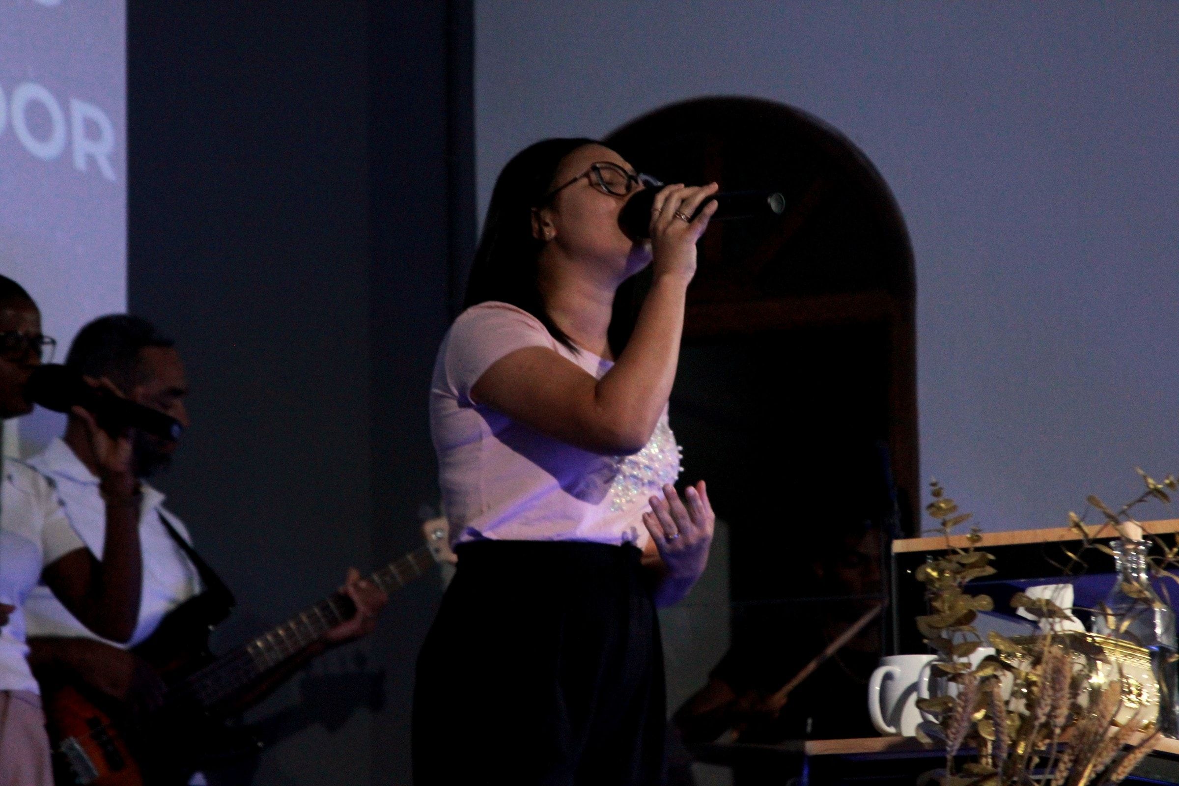 Uma cantora do louvor à frente do arco do púlpito